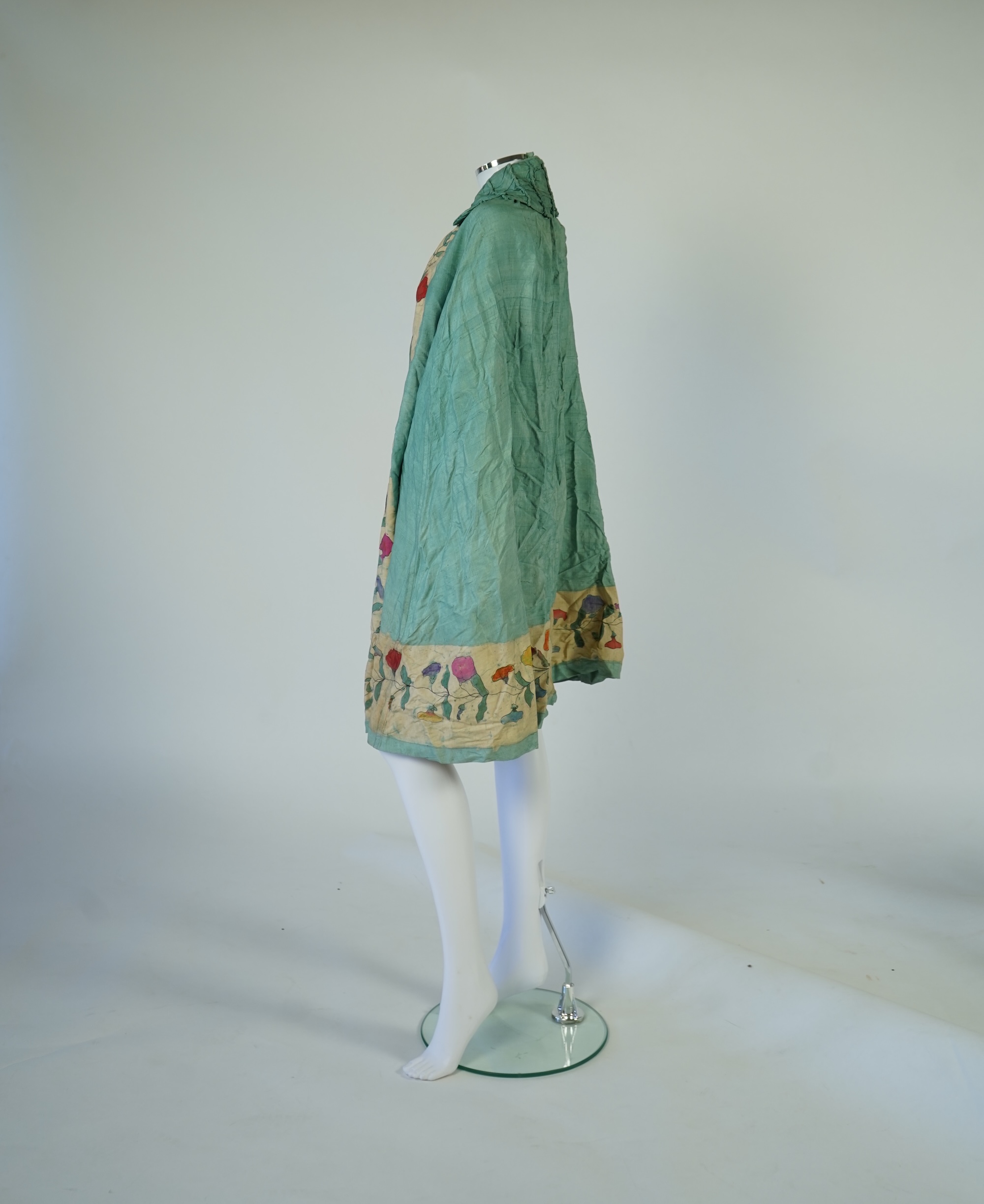 A 1920’s light green silk evening cape with hand batik borders and label: Tito de Canival Mode, together with a navy ladies two piece suit and a maroon satin evening dress. Cape 100cm long. Condition - cape good, navy tw